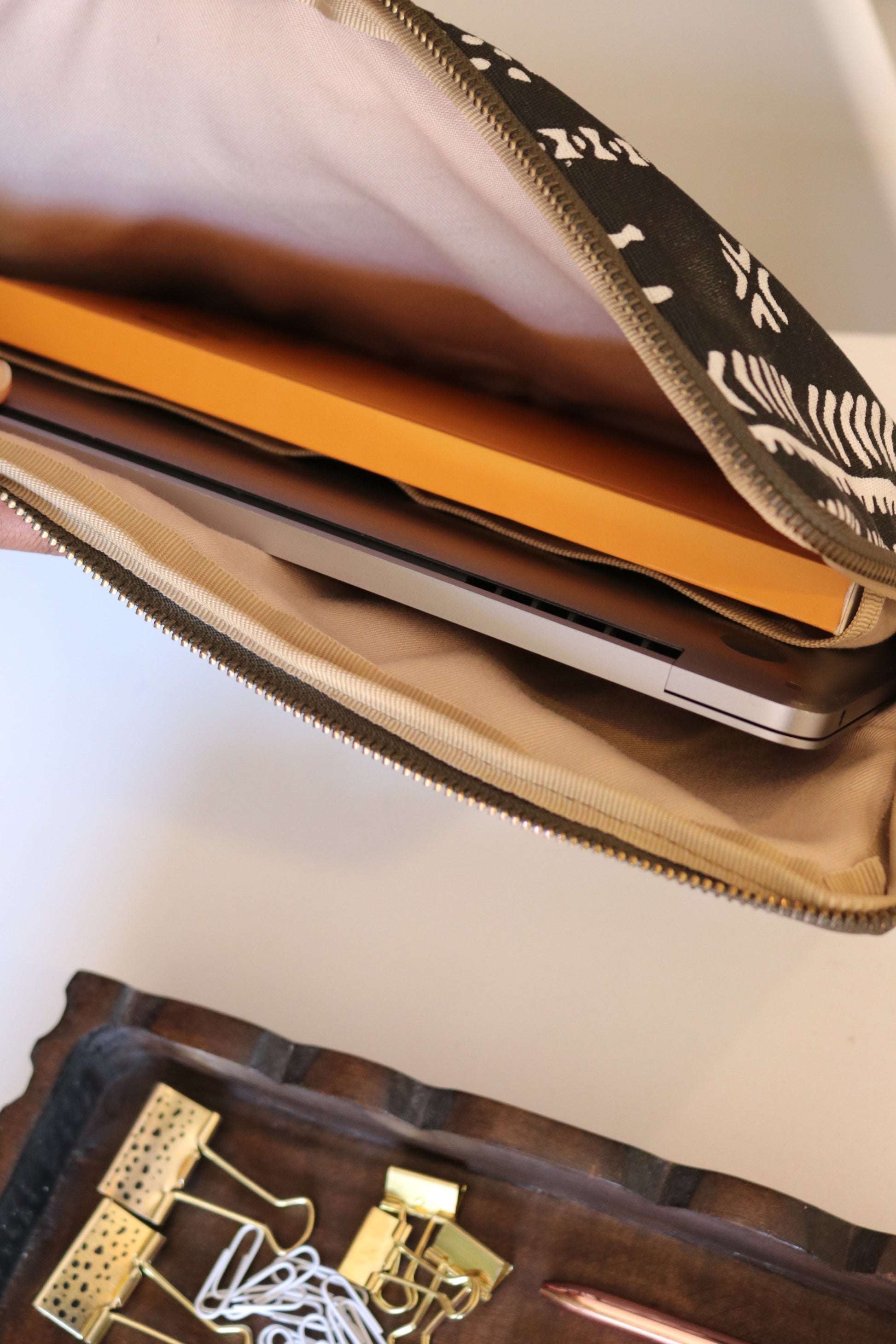 Open black laptop sleeve containing a laptop and office supplies on a white background