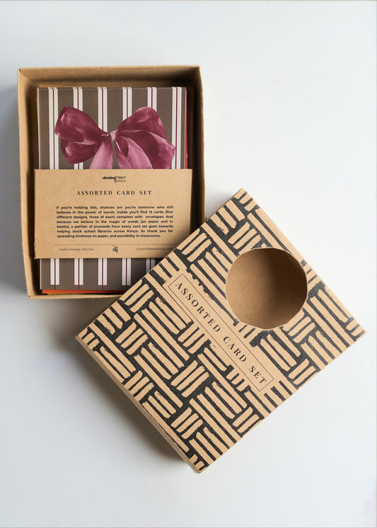Assorted greeting card pack with "In banana years, you're bread" HBD card, retro cassette tape, and large pink bow design on a white background.