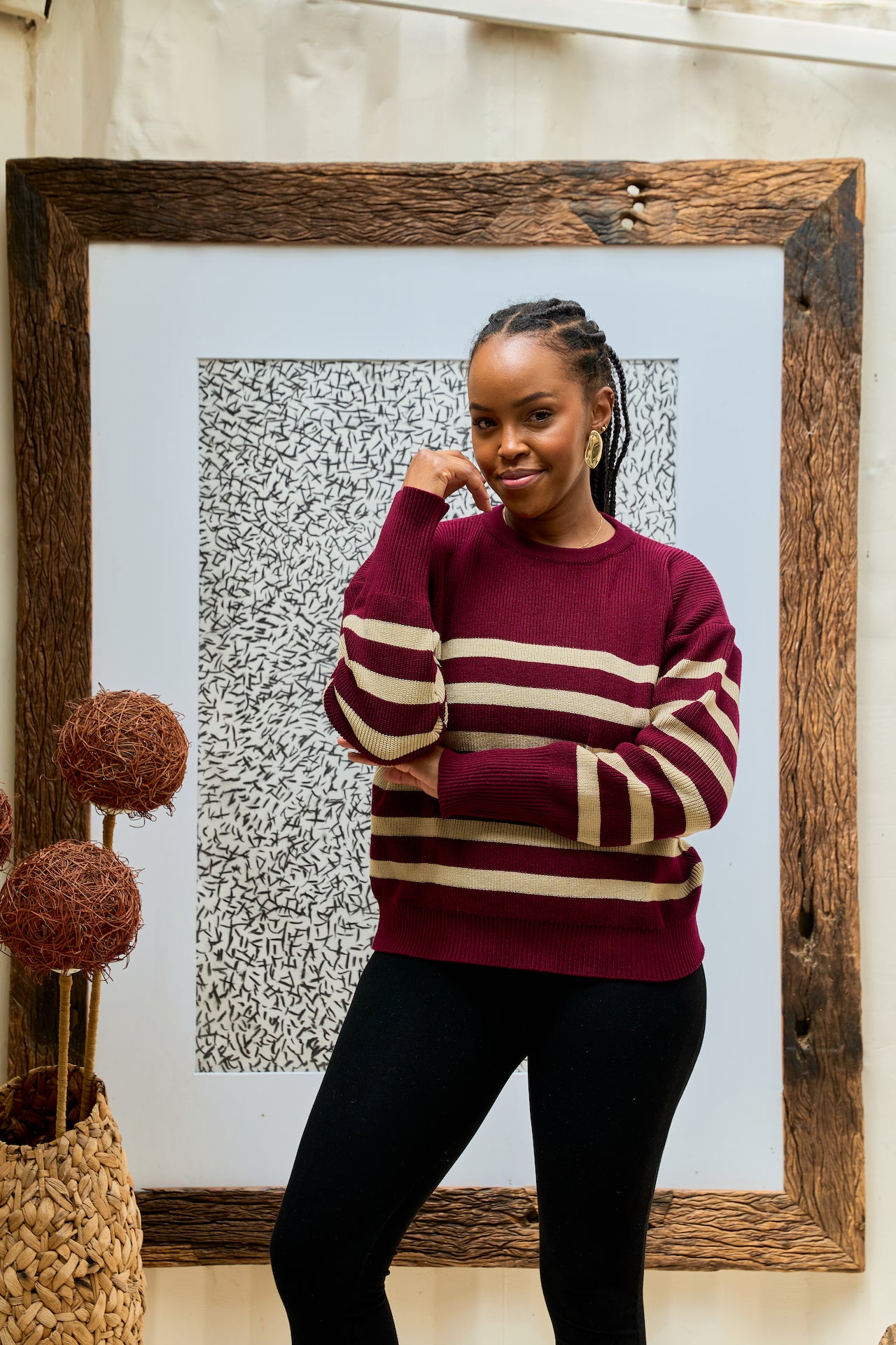 Woman wearing a maroon and beige striped sweater paired with black unitard