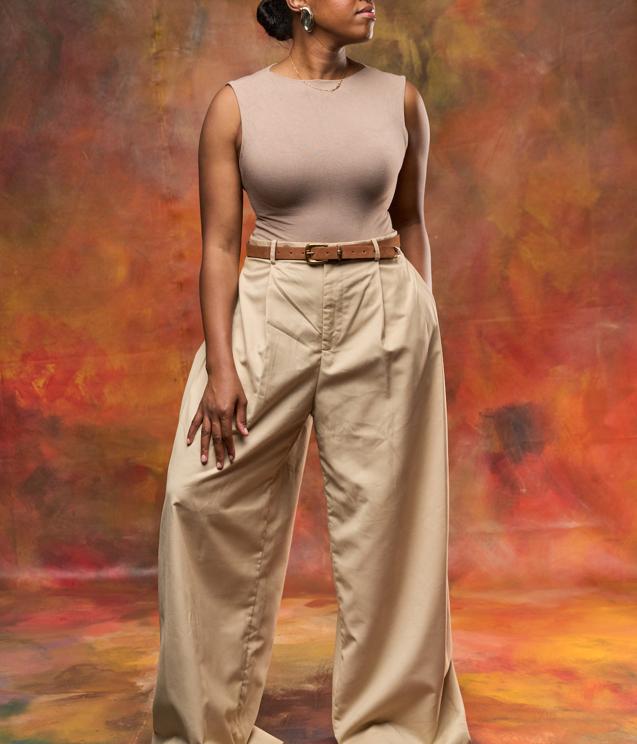 Woman wearing a stylish tan suede leather belt with a brass buckle.