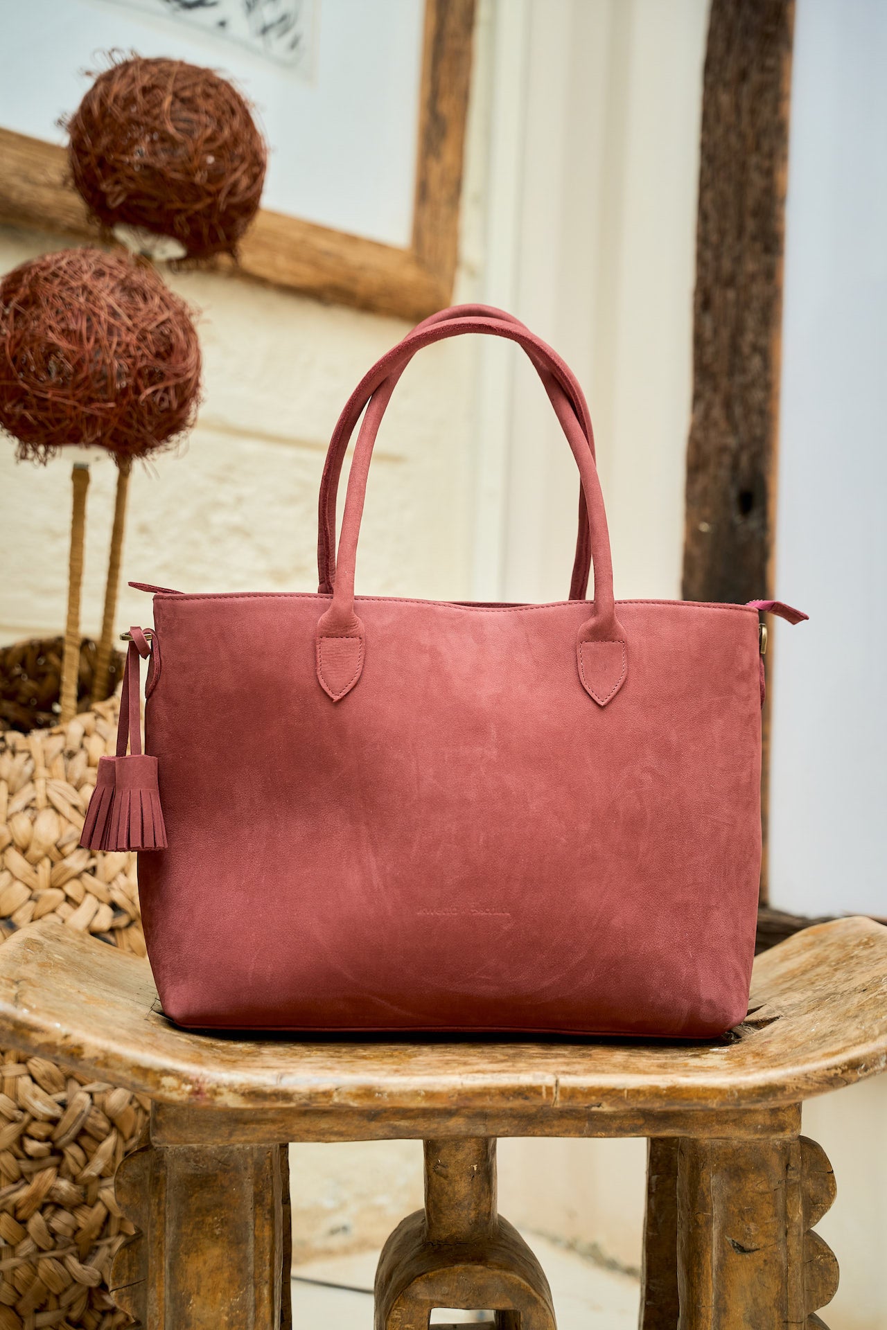 Red Suede leather handbag with a tassel on a wooden surface