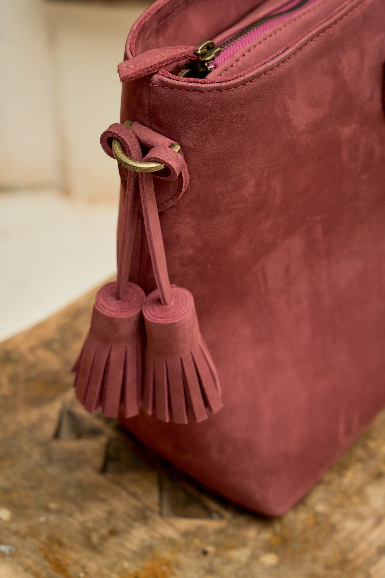 Close-up of a pink suede leather  handbag with tassel detail.