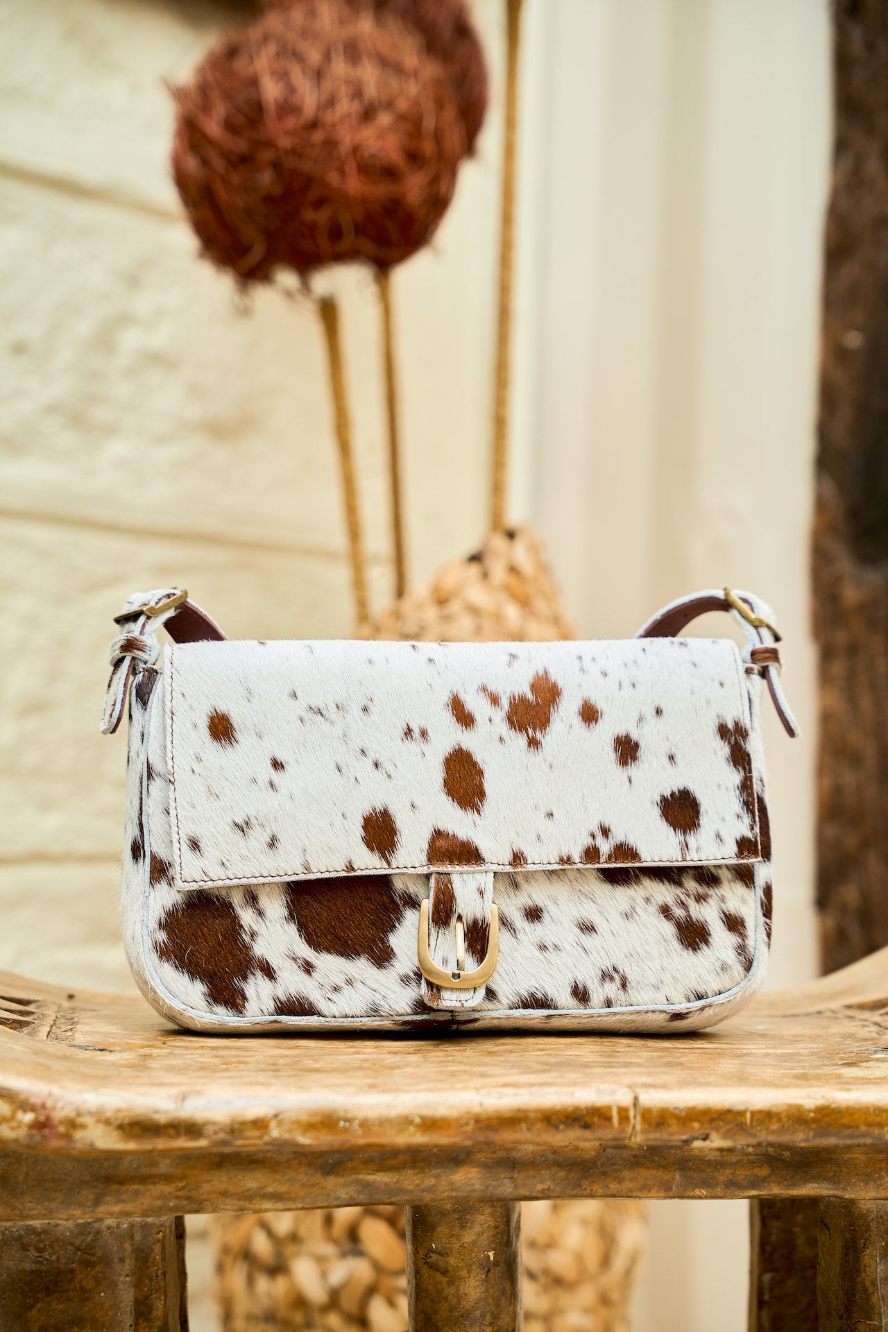 Manda cowhide mini handbag with hair-on-hide pattern, front view with brass buckle detail