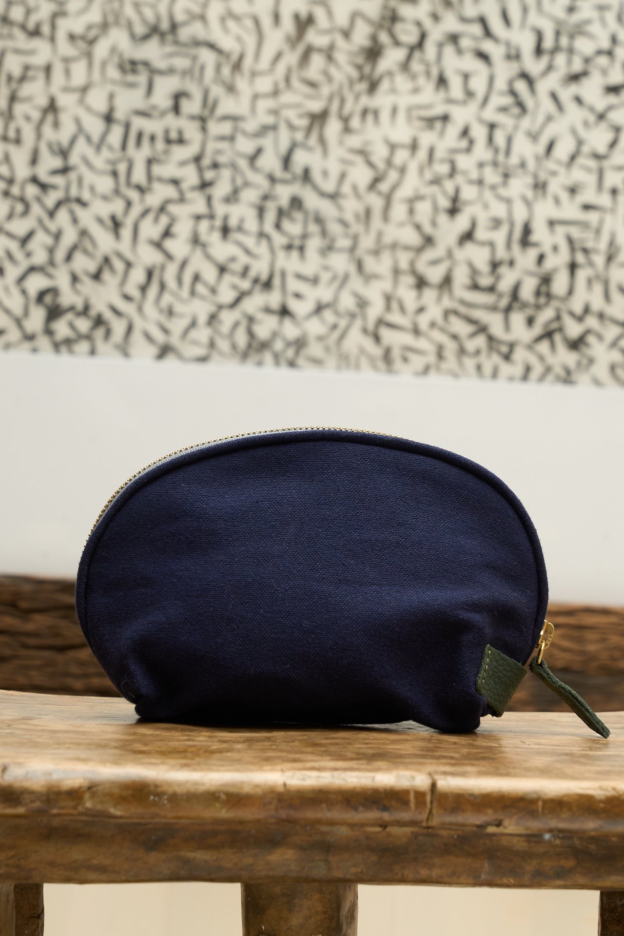 Navy blue organizer pouch with a gold zipper on a wooden surface with a textured wall background