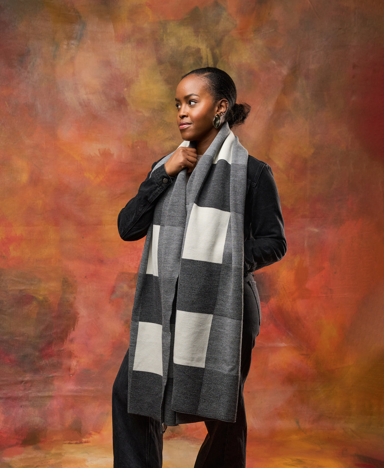 Oversized knit scarf worn wrapped around shoulders