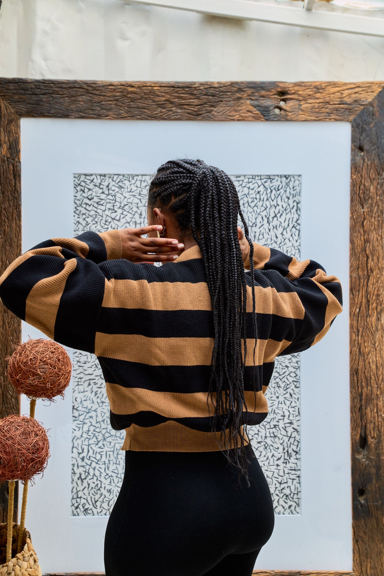 Person wearing a black and brown striped sweater standing in front of a textured wall.