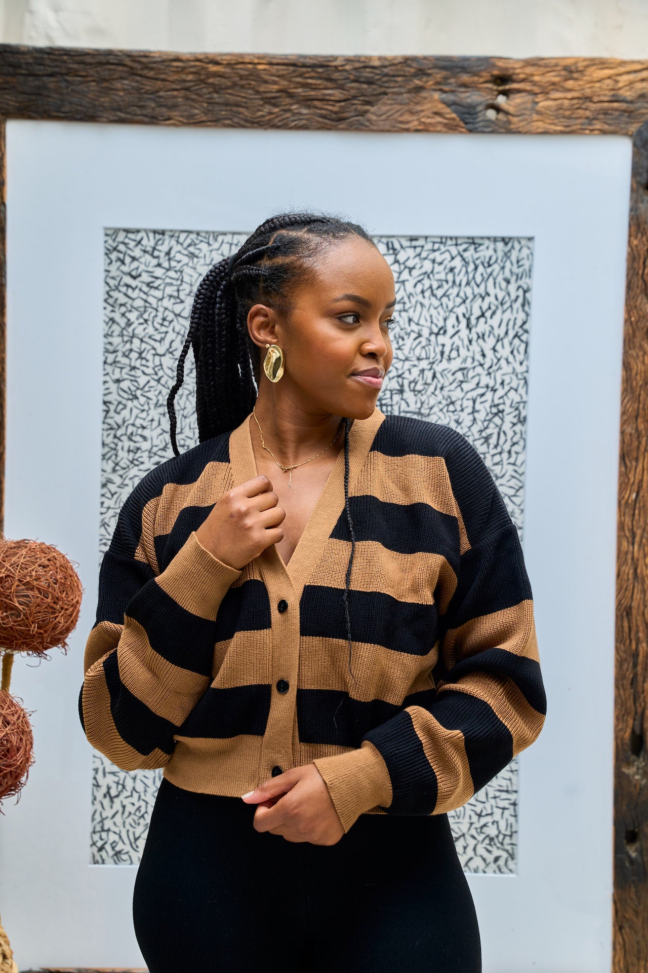 Woman wearing a black and brown striped cardigan against a textured wall.