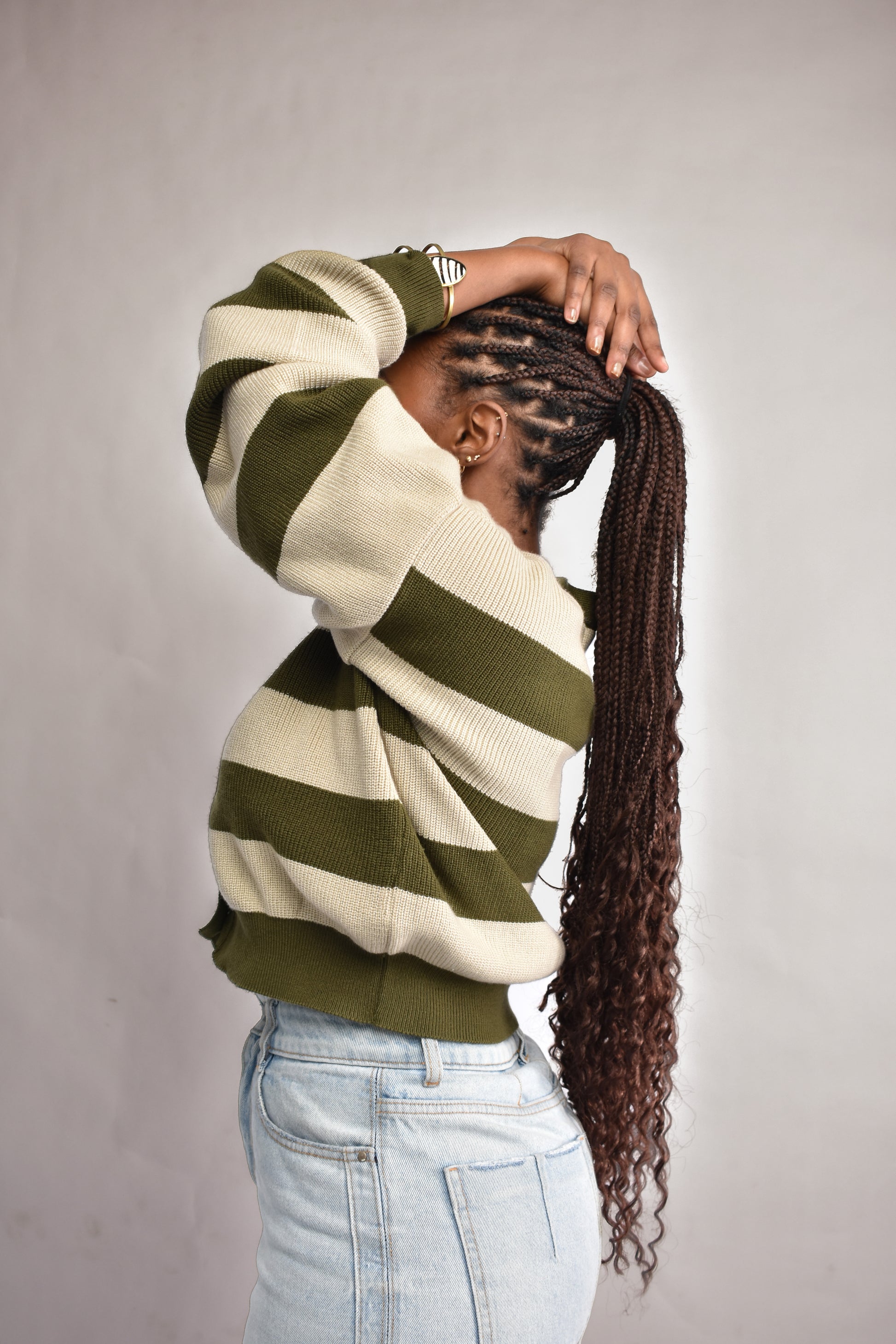 green and beige striped sweater paired with blue light wash jeans for women in Nairobi.