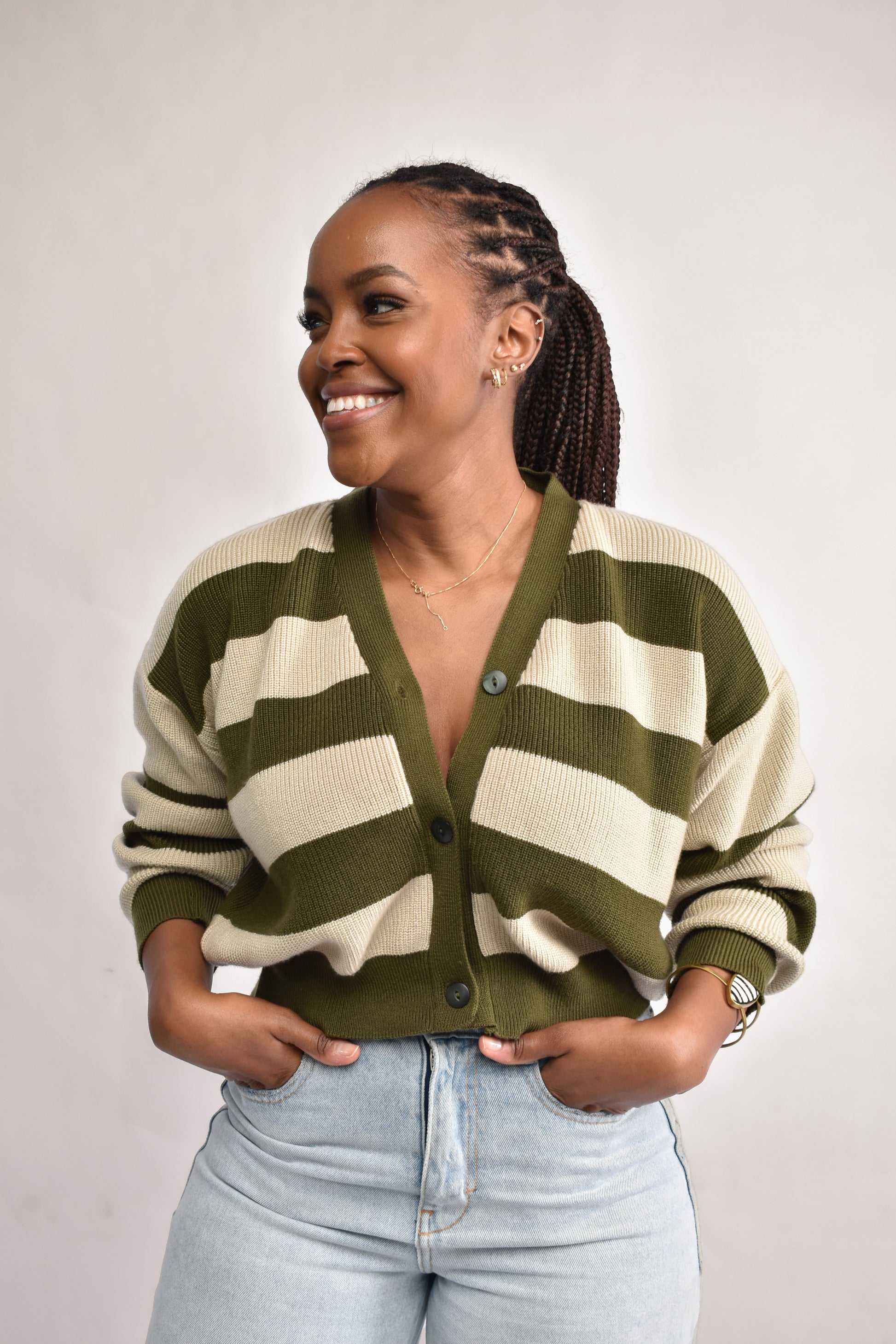 Woman wearing a green and beige striped cardigan against a plain background