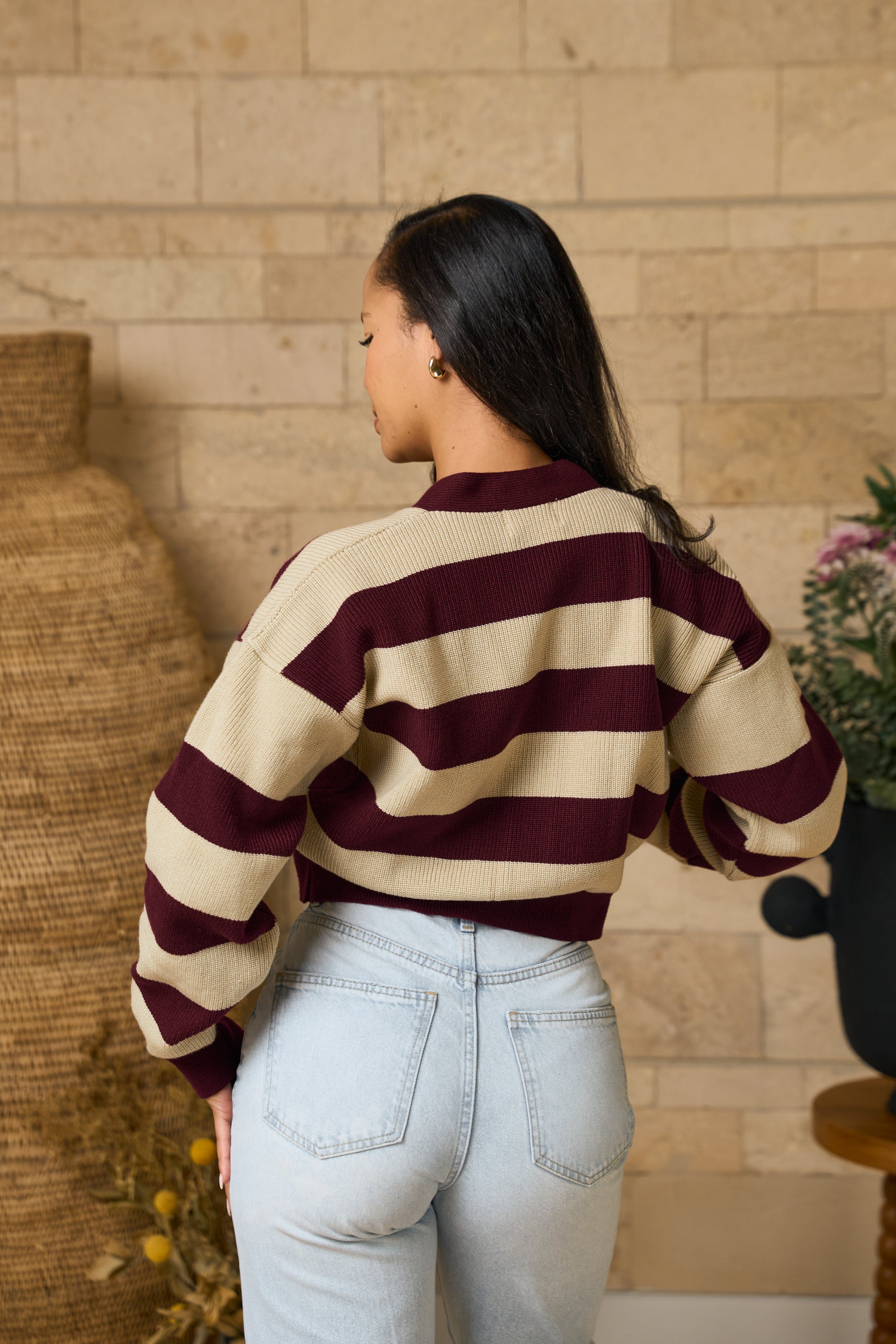 A woman wearing aStriped cropped cardigan in burgundy back view showing relaxed fit and oversized sleeves