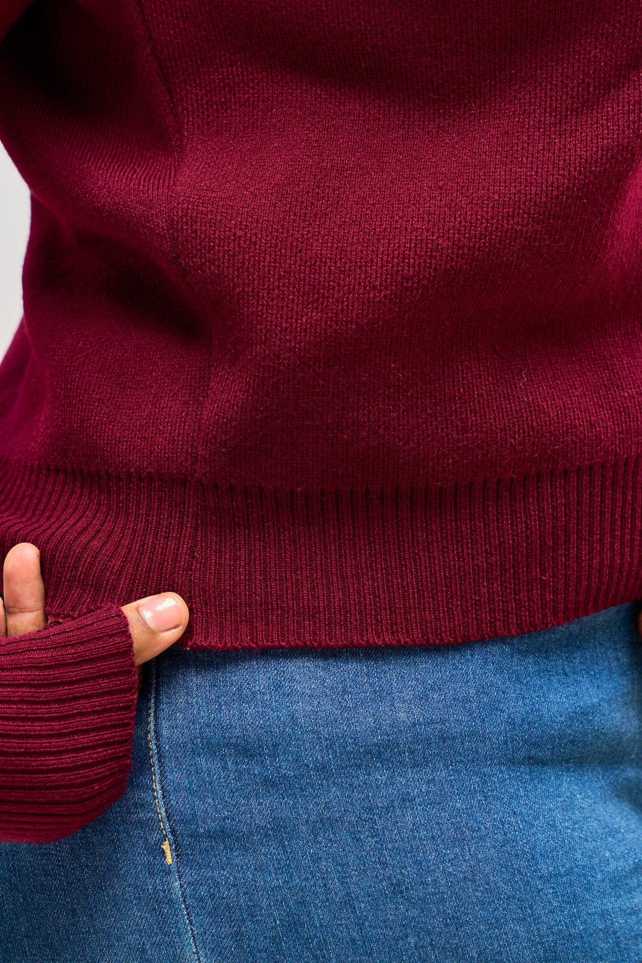 Close-up of a woman wearing a burgundy sweater and blue jeans.