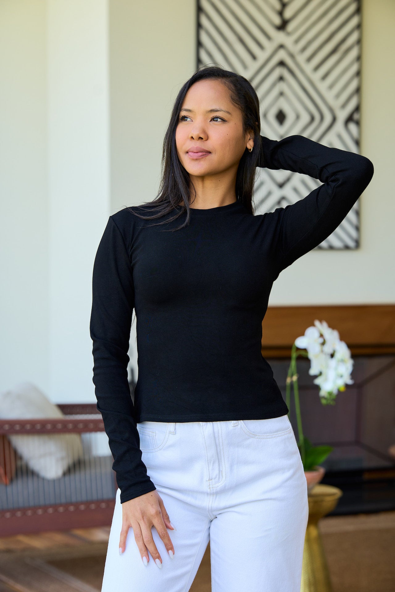 A woman wearing a fitted black long-sleeve tee paired with white pants.