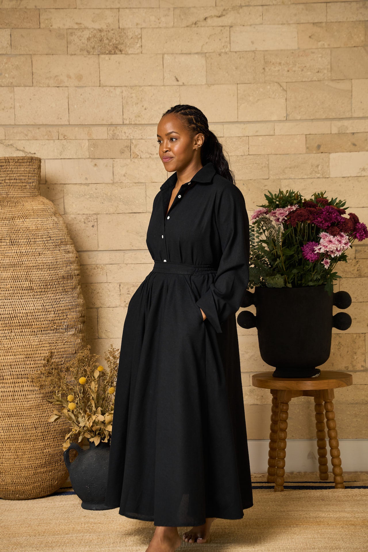 A black midi skirt made of linen blend, designed with pockets, pleats, and an elastic waistband for comfort.