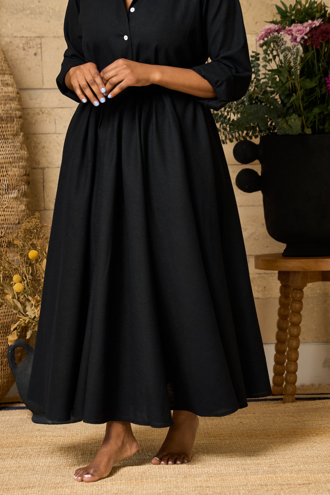 A black midi skirt made of linen blend, designed with pockets, pleats, and an elastic waistband for comfort.