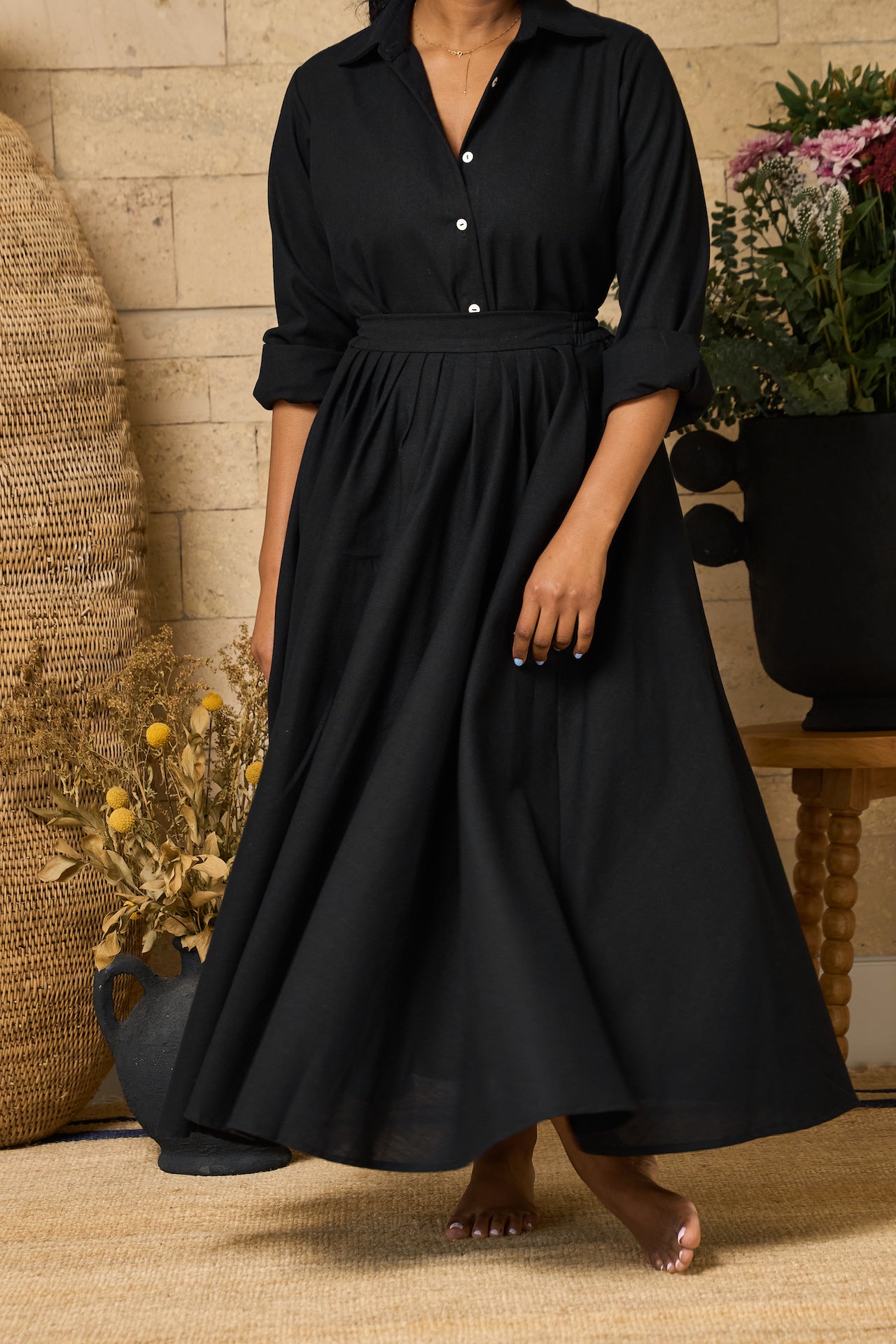 A black midi skirt made of linen blend, designed with pockets, pleats, and an elastic waistband for comfort.