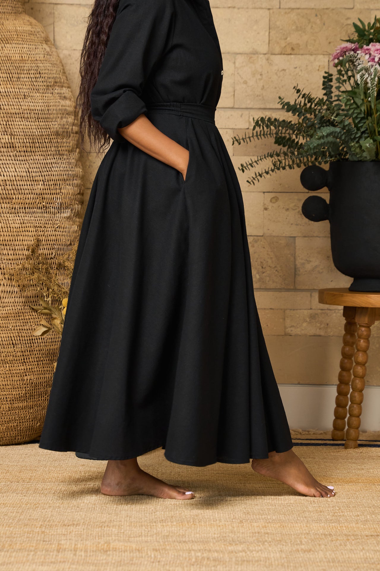 A black midi skirt made of linen blend, designed with pockets, pleats, and an elastic waistband for comfort.
