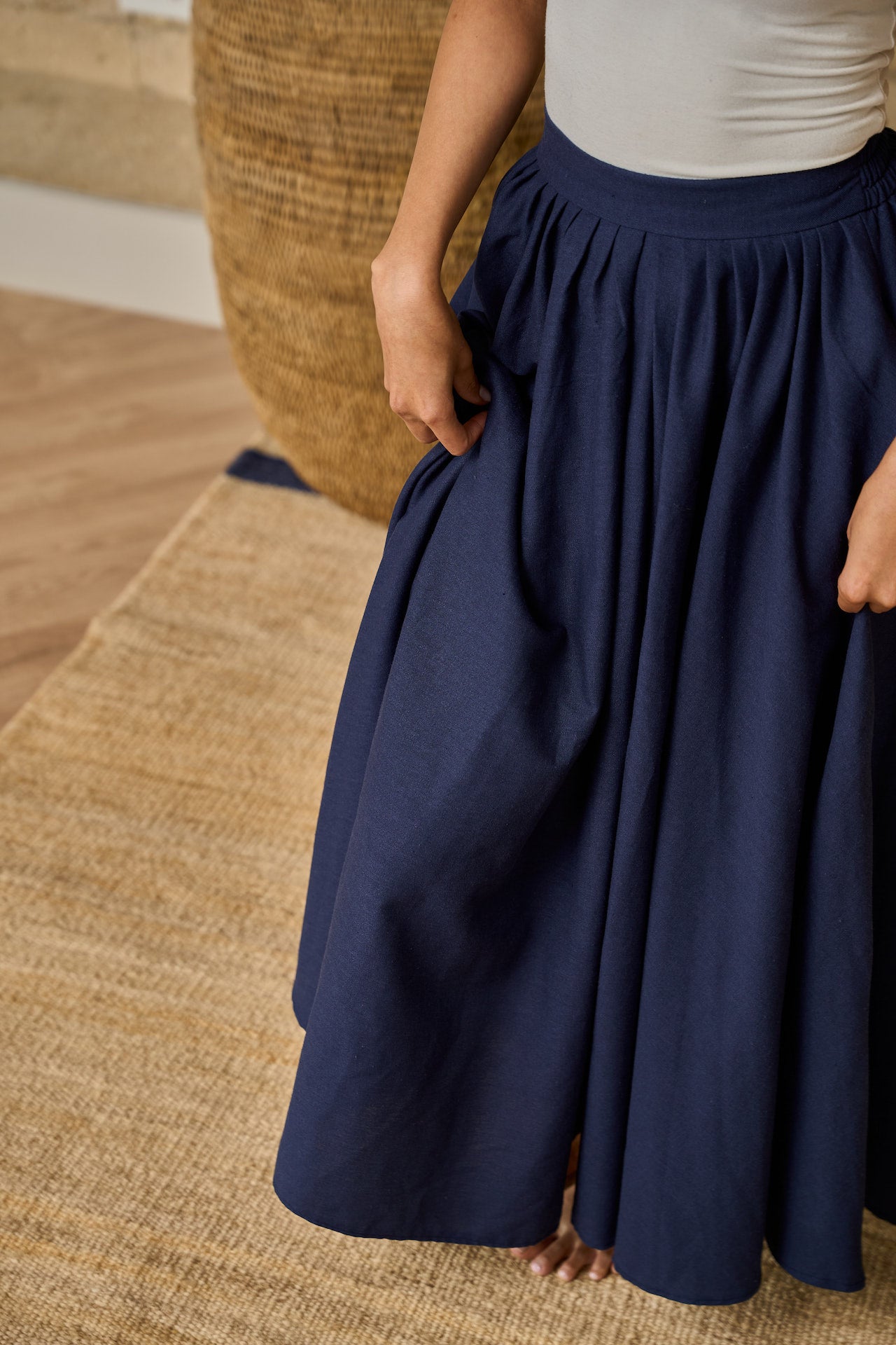 A navy midi skirt made of linen blend, designed with pockets, pleats, and an elastic waistband for comfort.