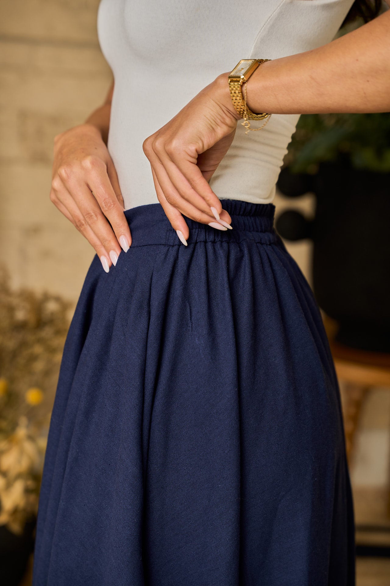 A navy midi skirt made of linen blend, designed with pockets, pleats, and an elastic waistband for comfort.