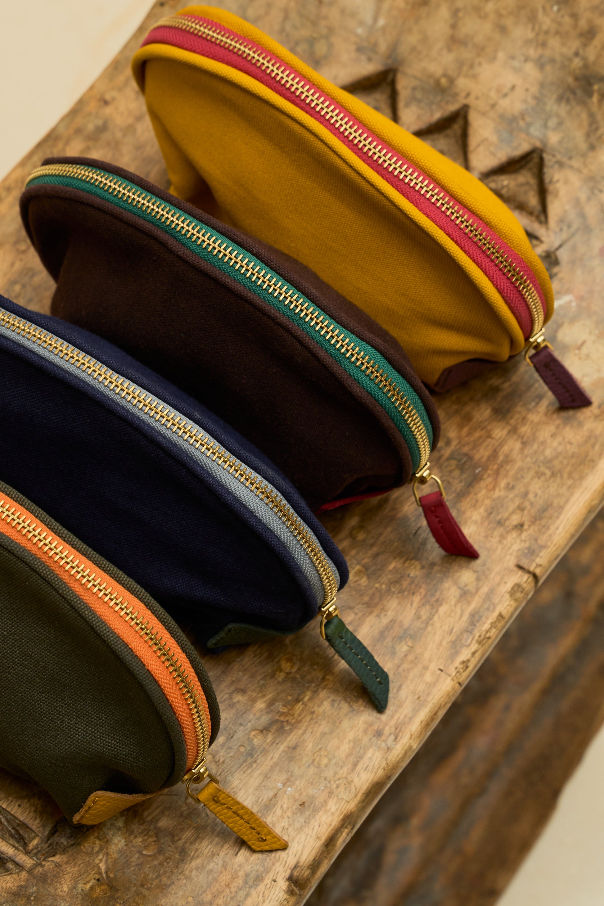 Four colorful zippered organizer pouches on a wooden surface