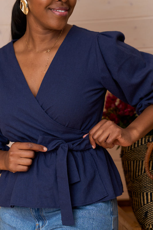 Woman wearing Yana Linen Blend Wrap Top in magenta with three-quarter puff sleeves and V neckline, styled with blue jeans.