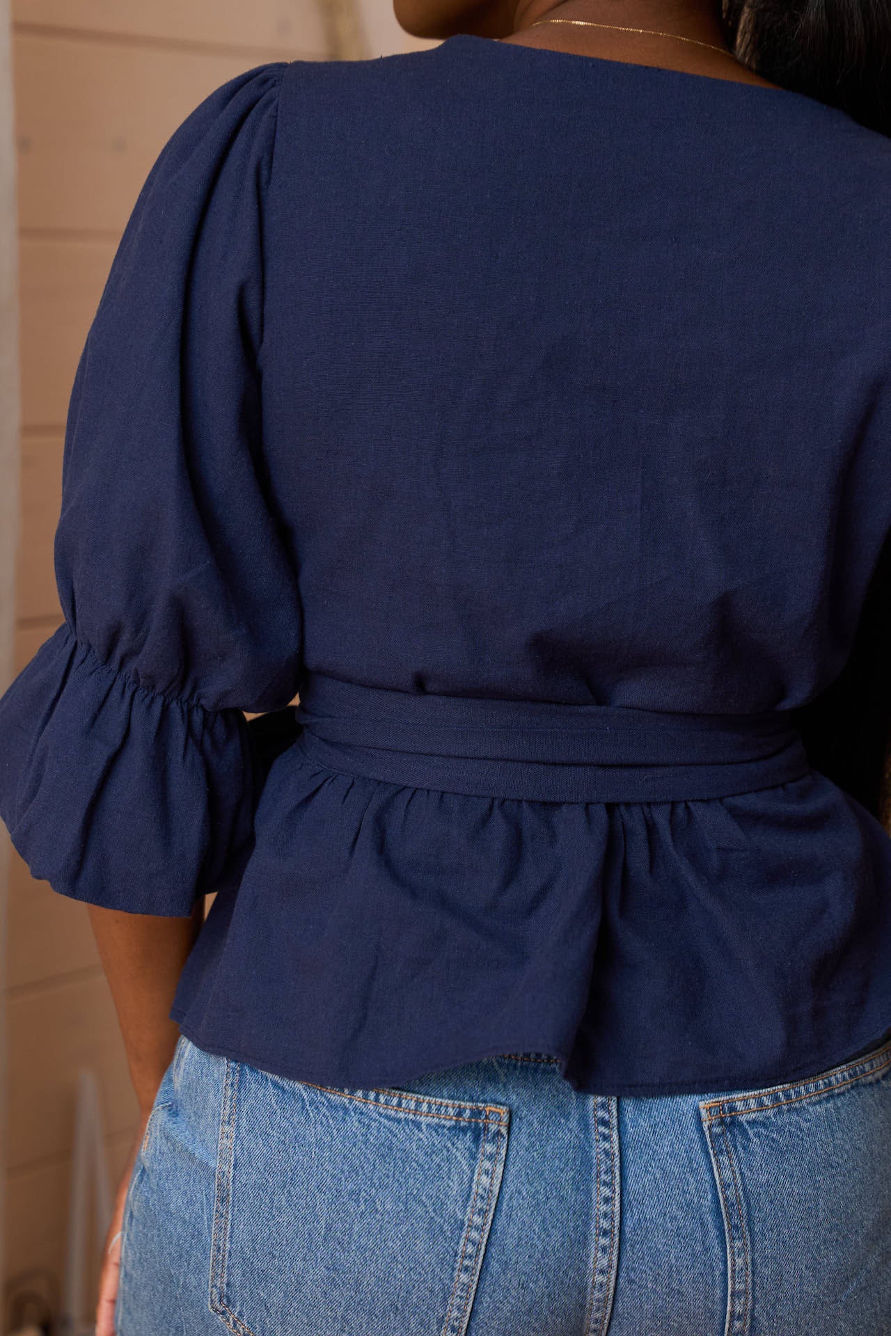 Close-up of the Yana Navy Linen Blend Wrap Top highlighting the adjustable waist tie and fabric texture