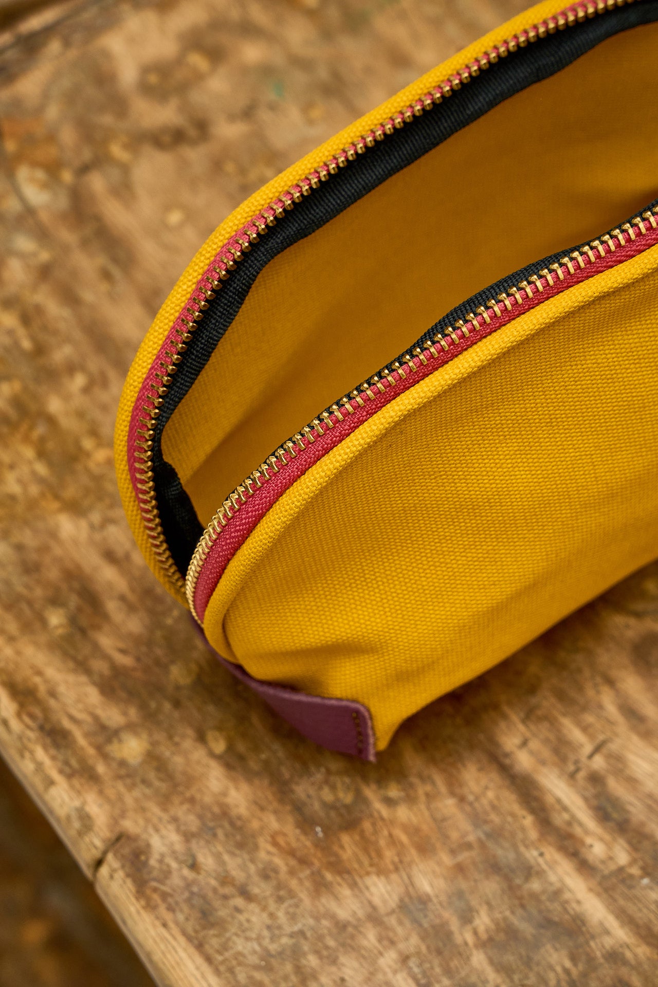 Yellow pouch with a red zipper on a wooden surface
