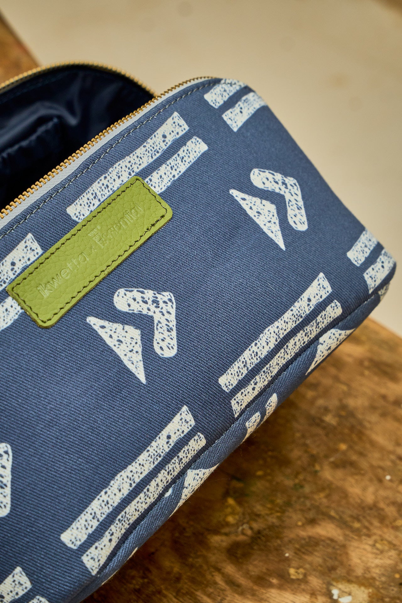 Blue travel bag with white geometric patterns and a green patch on a wooden surface