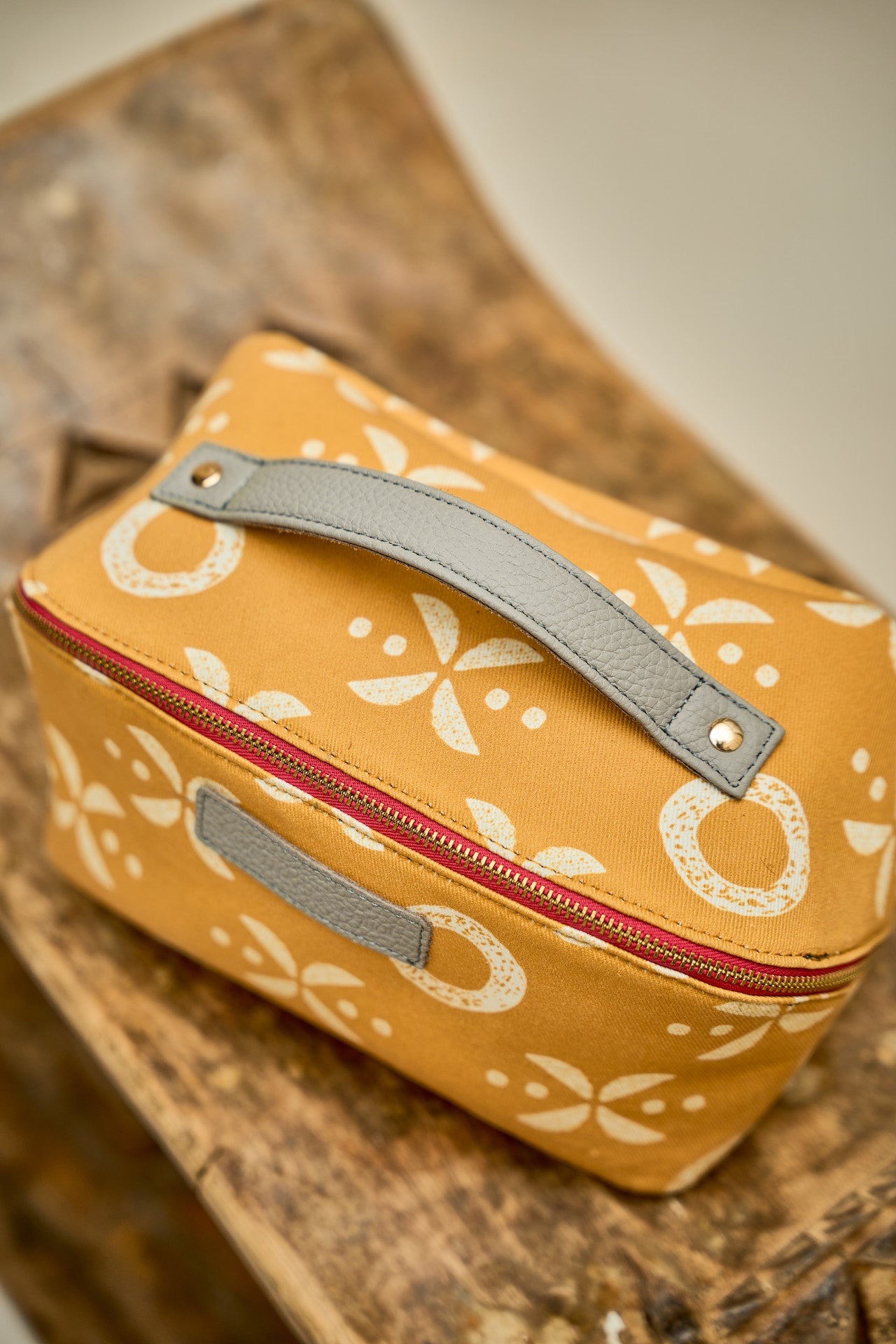 Yellow floral-patterned toiletry bag with grey leather handle  top view